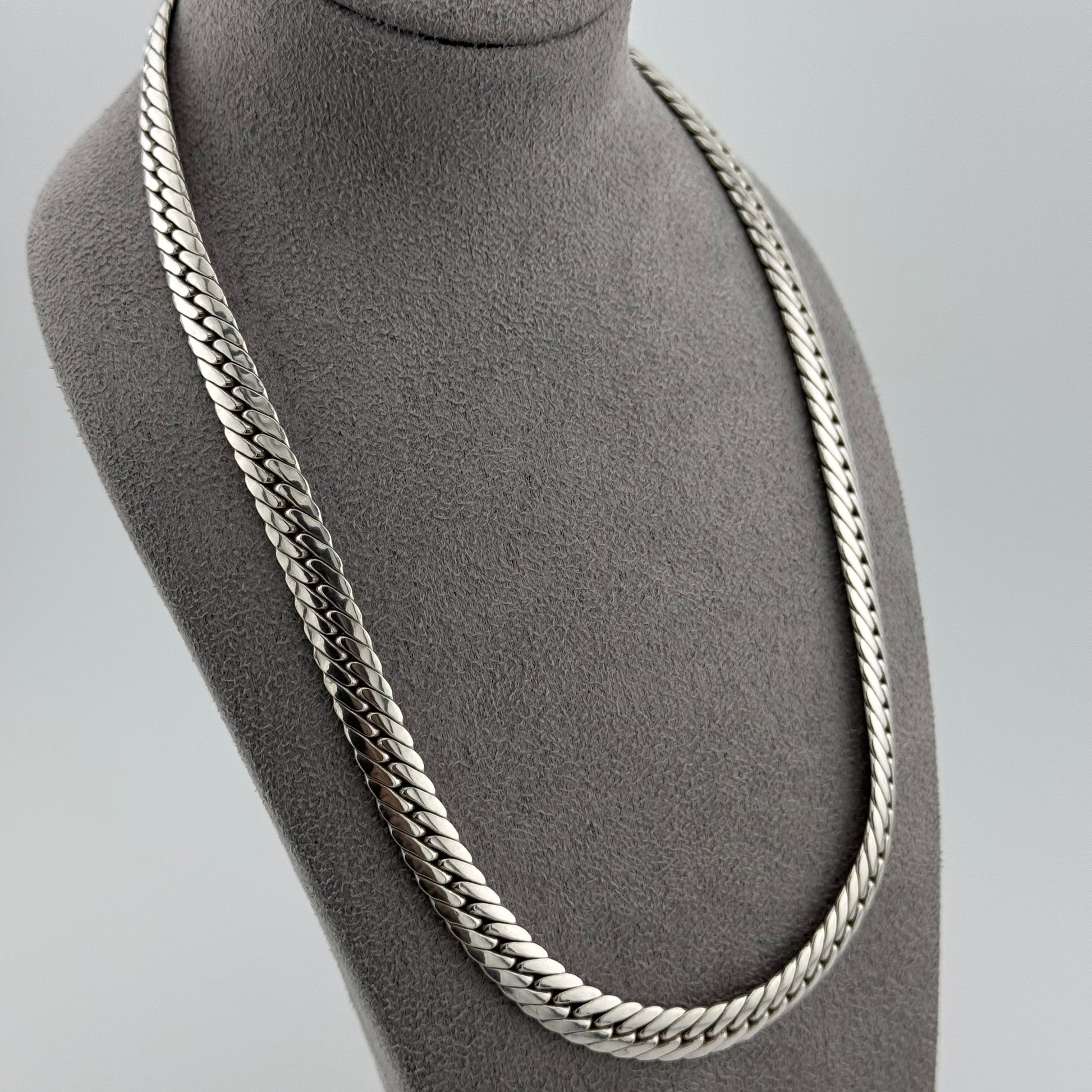 Herringbone chain in sterling silver weighing 50g sat on a grey suede bust