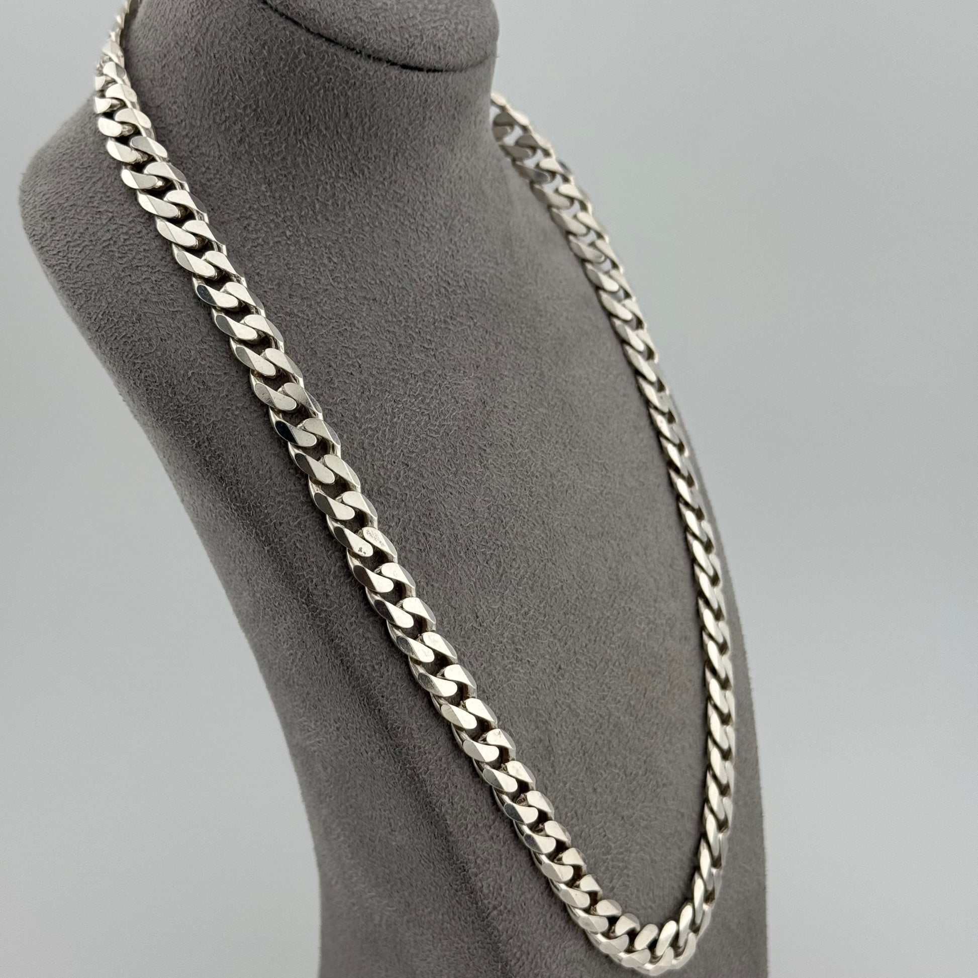 Silver chain necklace on a mannequin bust against a gray background