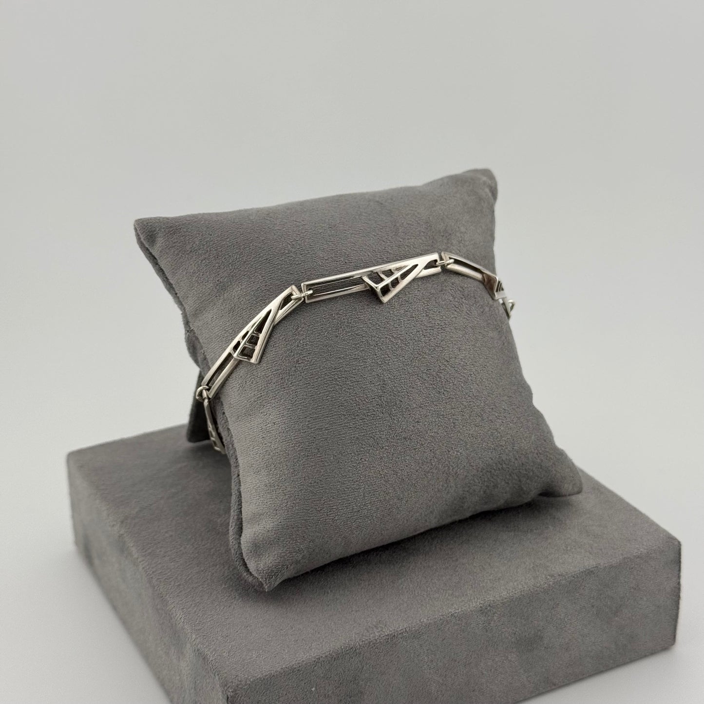 sterling silver geometric bracelet on a grey suede cushion
