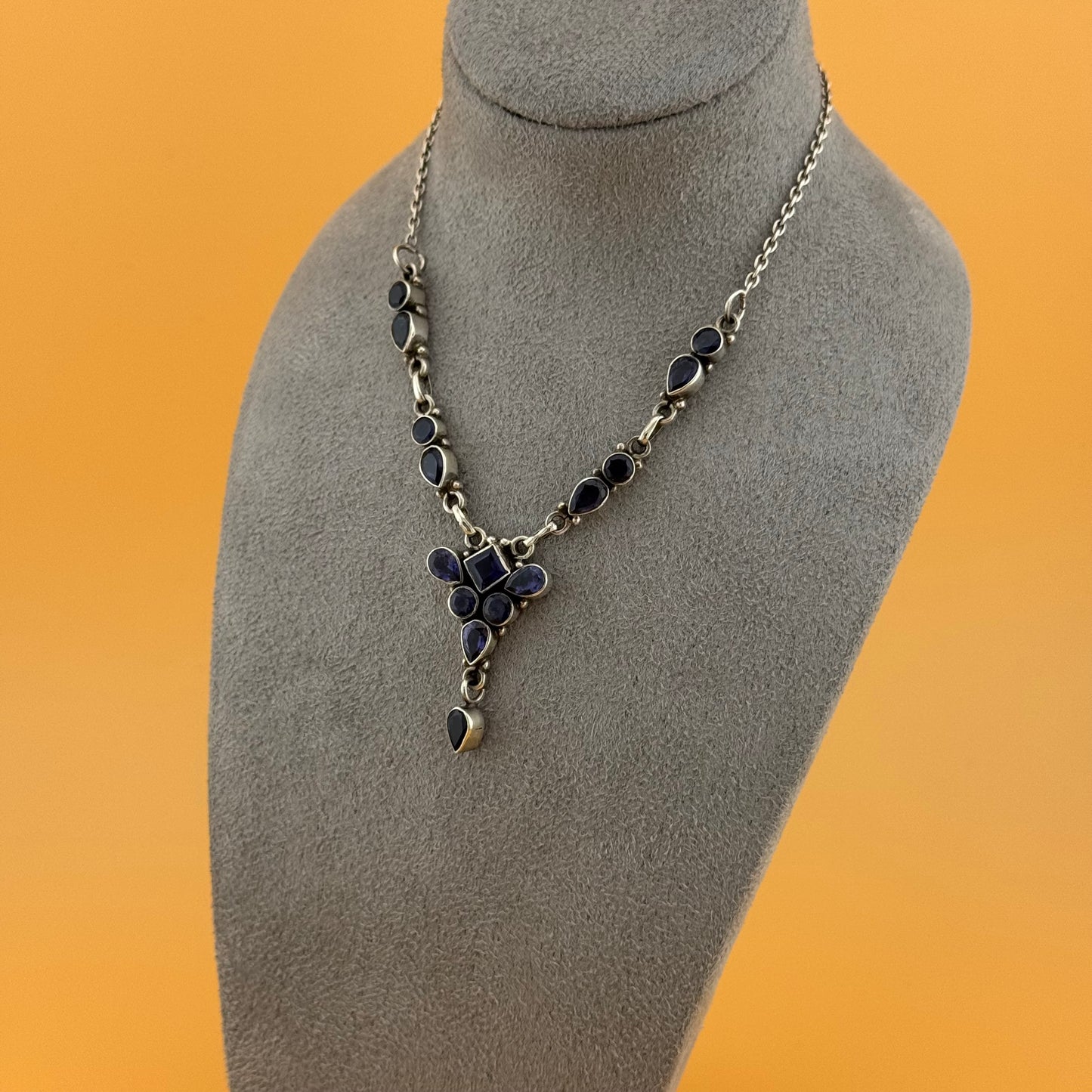 Necklace with a pendant on a gray mannequin bust against an orange background