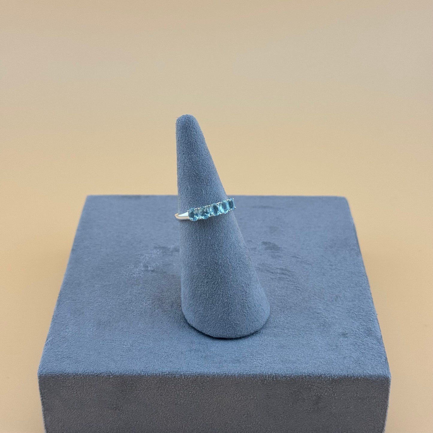 Aquamarine Ring on a blue cone-shaped stand against a beige background