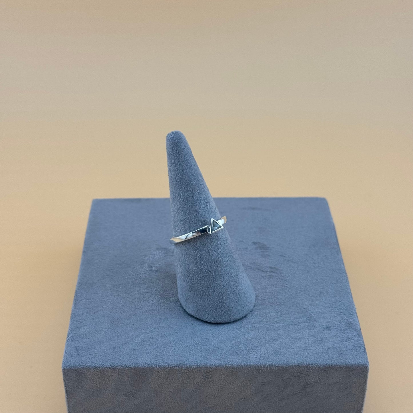Silver ring on a blue ring stand against a beige background