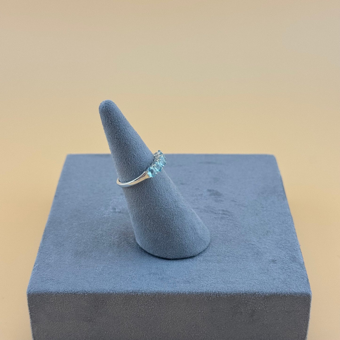 aquamarine Ring on a blue cone-shaped stand against a beige background