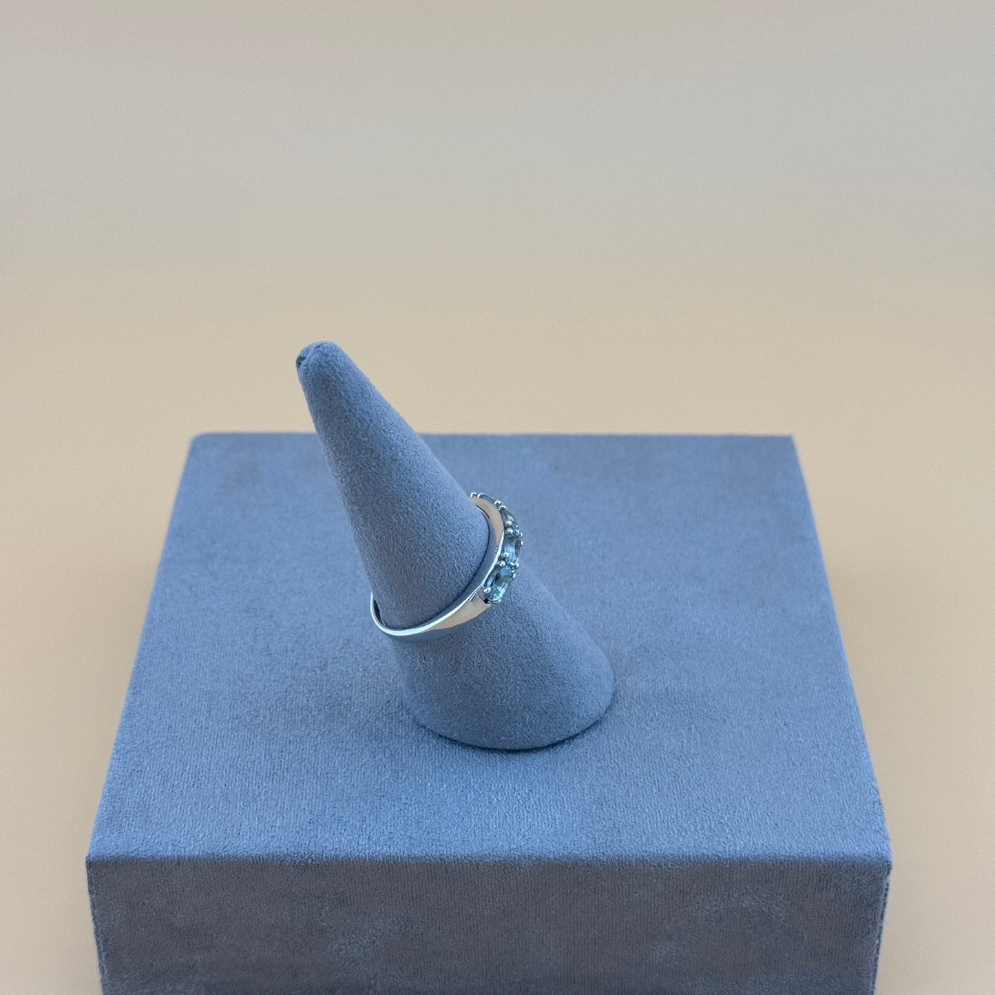Ring on a blue cone-shaped stand with a beige background