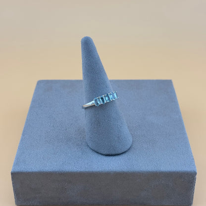 Aquamarine 5 stone Ring on a blue stand with a beige background