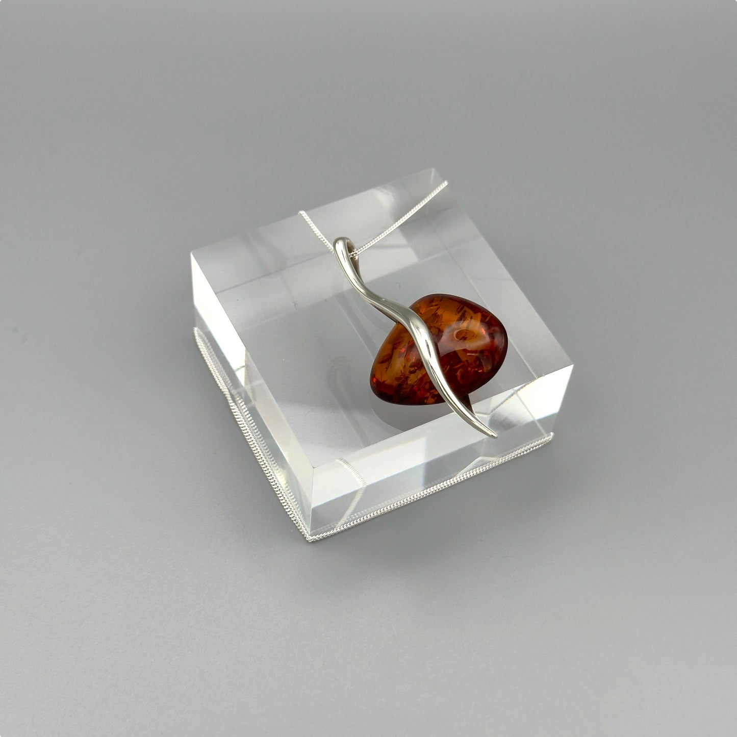 Twisted frame amber necklace on grey background