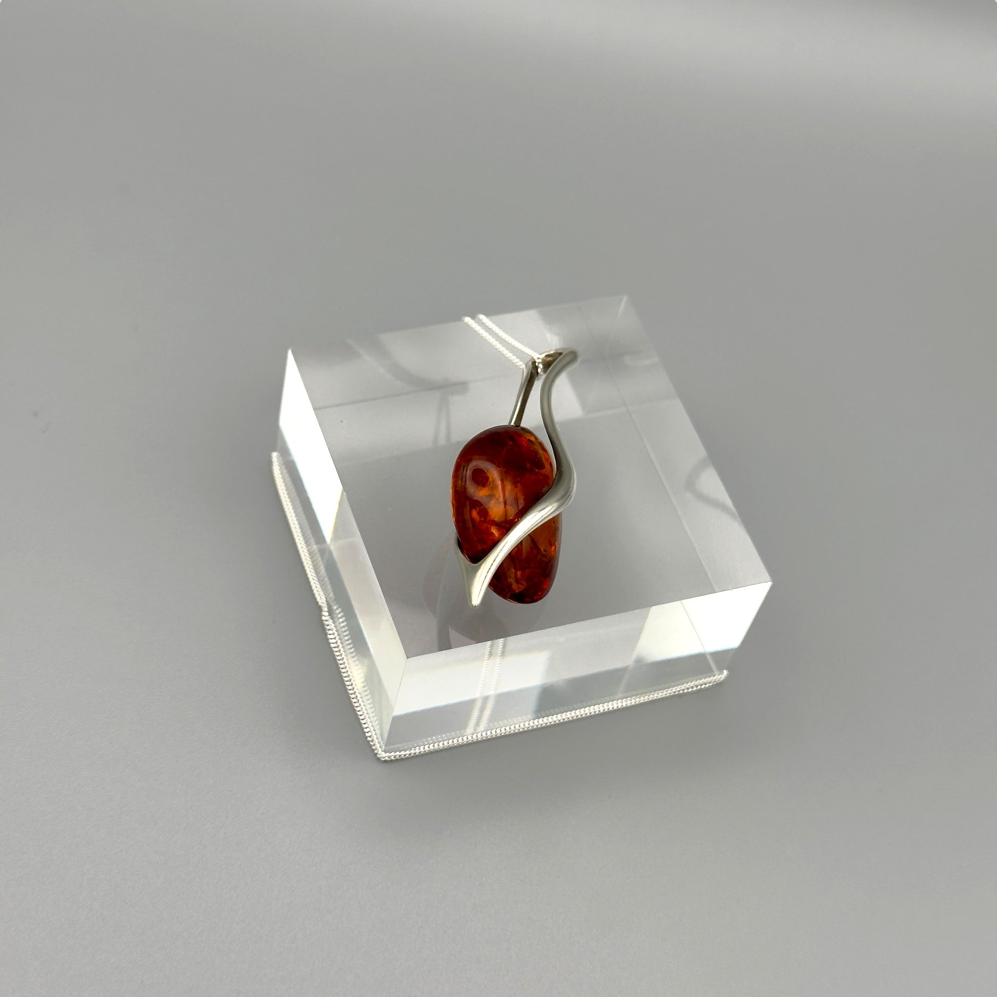 Artistic amber pendant with minimalist silver lines

