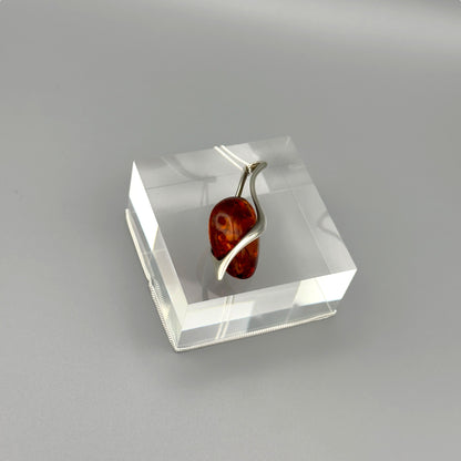 Artistic amber pendant with minimalist silver lines

