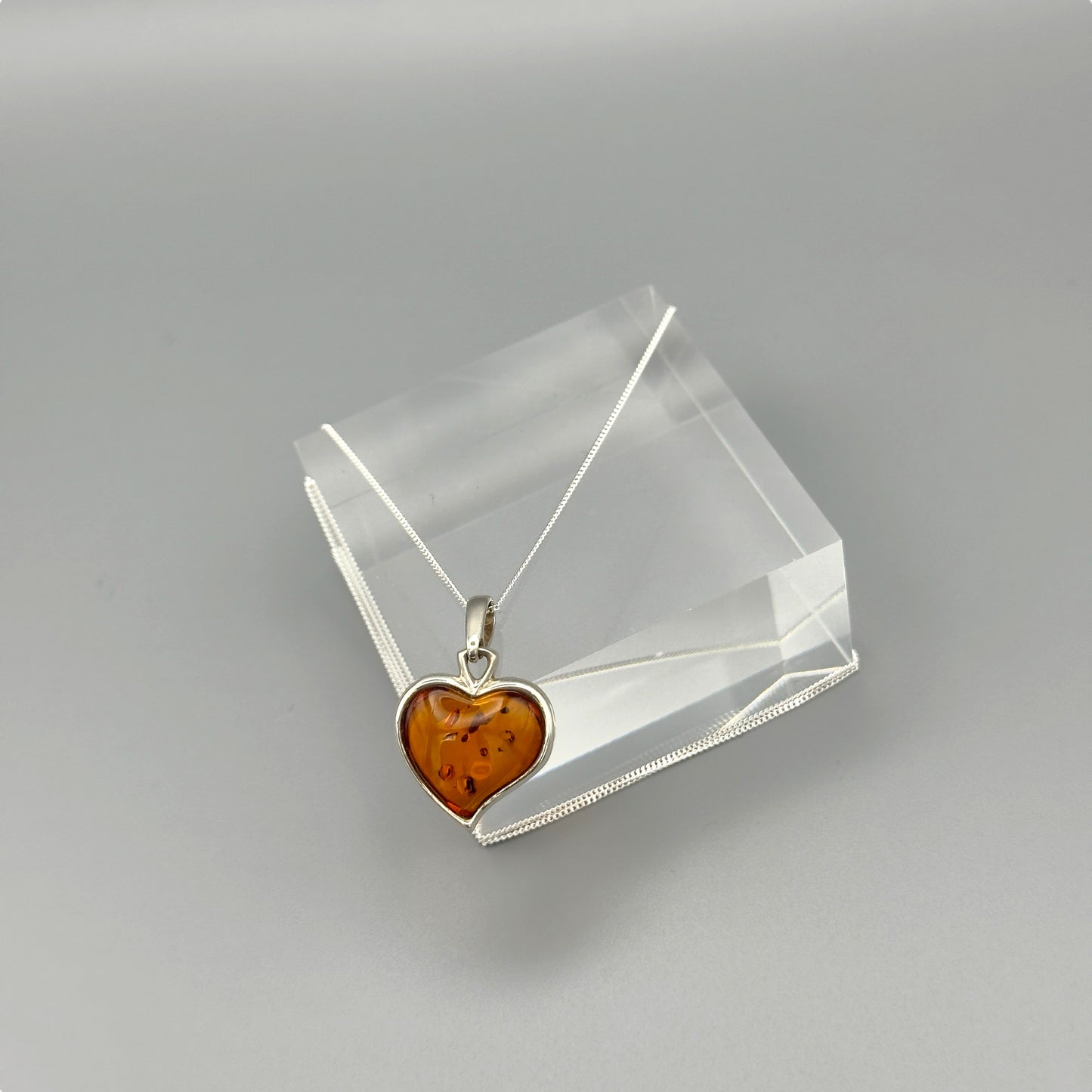 Heart-shaped amber pendant on clear block