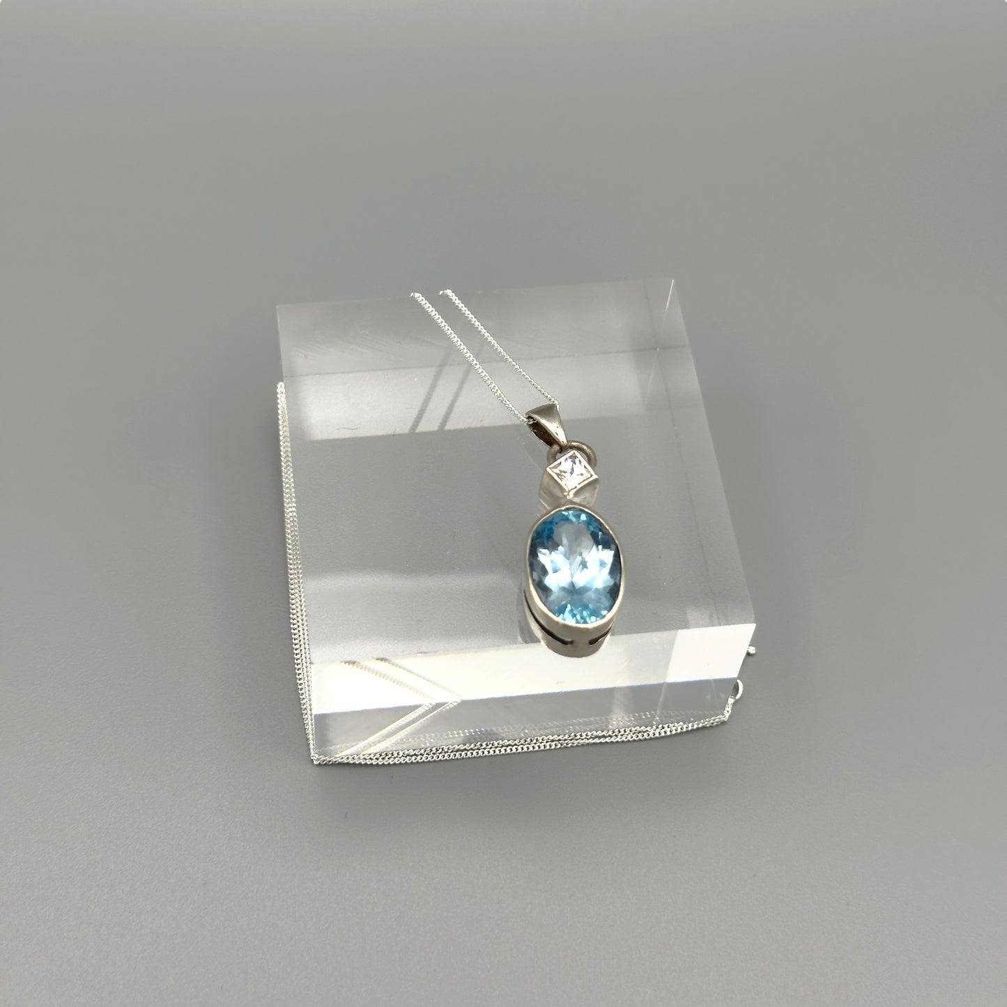 Close-up of aquamarine oval pendant on silver chain