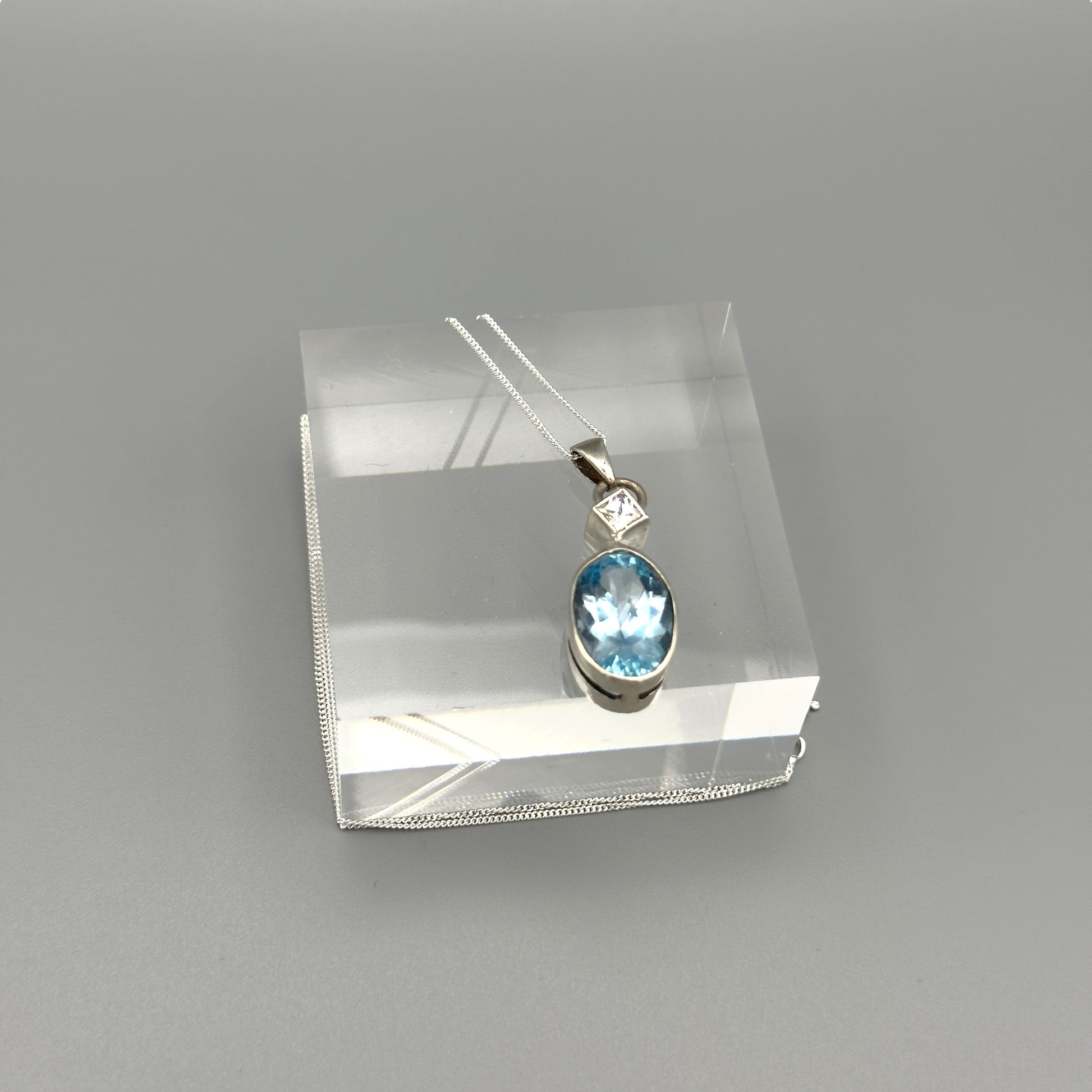 Close-up of aquamarine oval pendant on silver chain