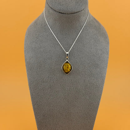 Necklace with an amber pendant on a gray mannequin bust against an orange background