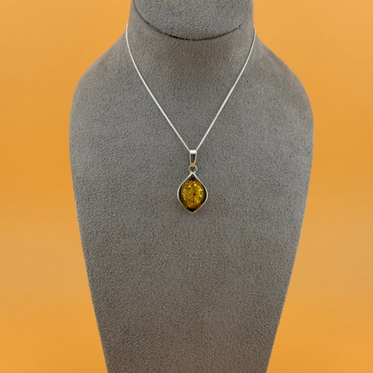 Necklace with an amber pendant on a gray mannequin bust against an orange background