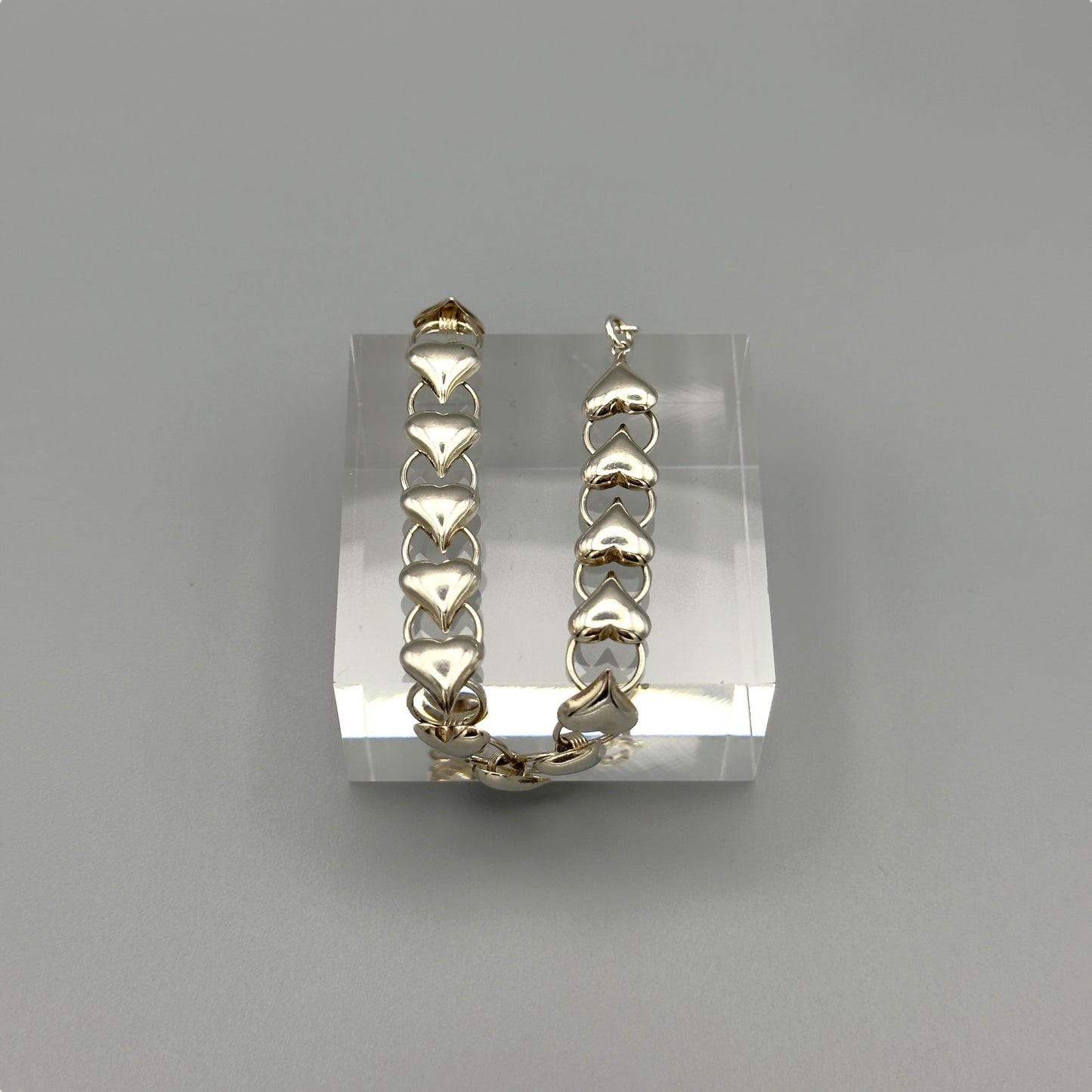 Shiny silver heart bracelet on grey background