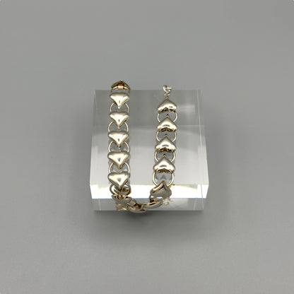 Shiny silver heart bracelet on grey background