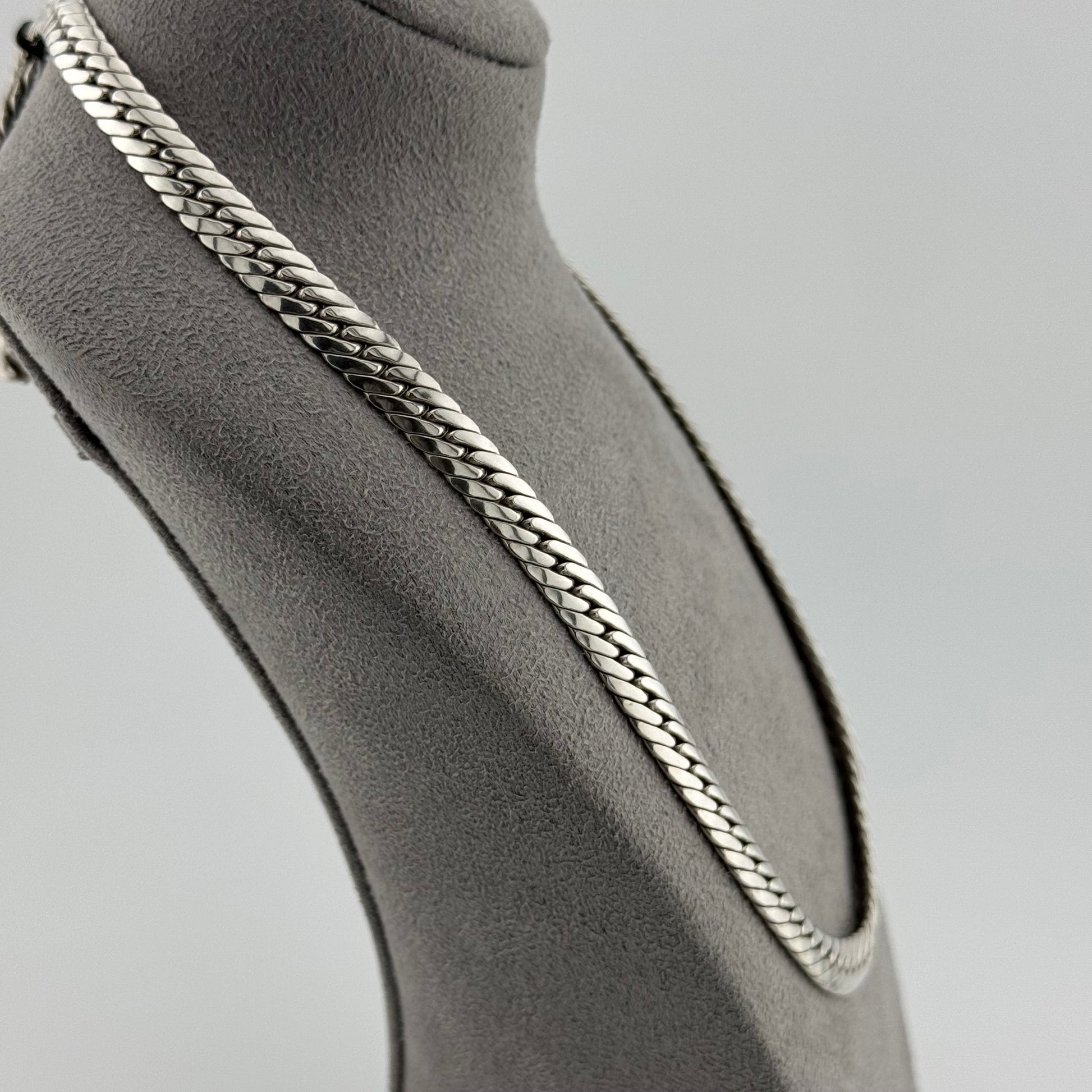 Herringbone chain in sterling silver weighing 50g sat on a grey suede bust