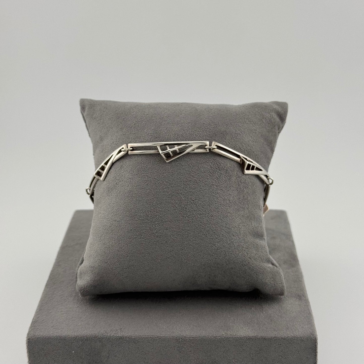 sterling silver geometric bracelet on a grey suede cushion 