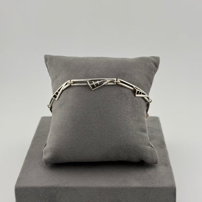 sterling silver geometric bracelet on a grey suede cushion 
