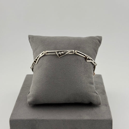 sterling silver geometric bracelet on a grey suede cushion 
