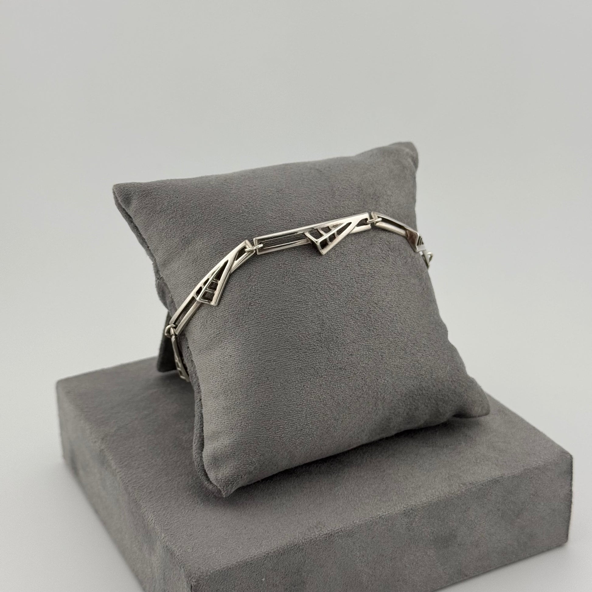 sterling silver geometric bracelet on a grey suede cushion 