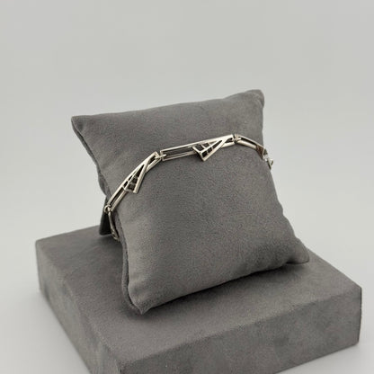 sterling silver geometric bracelet on a grey suede cushion 