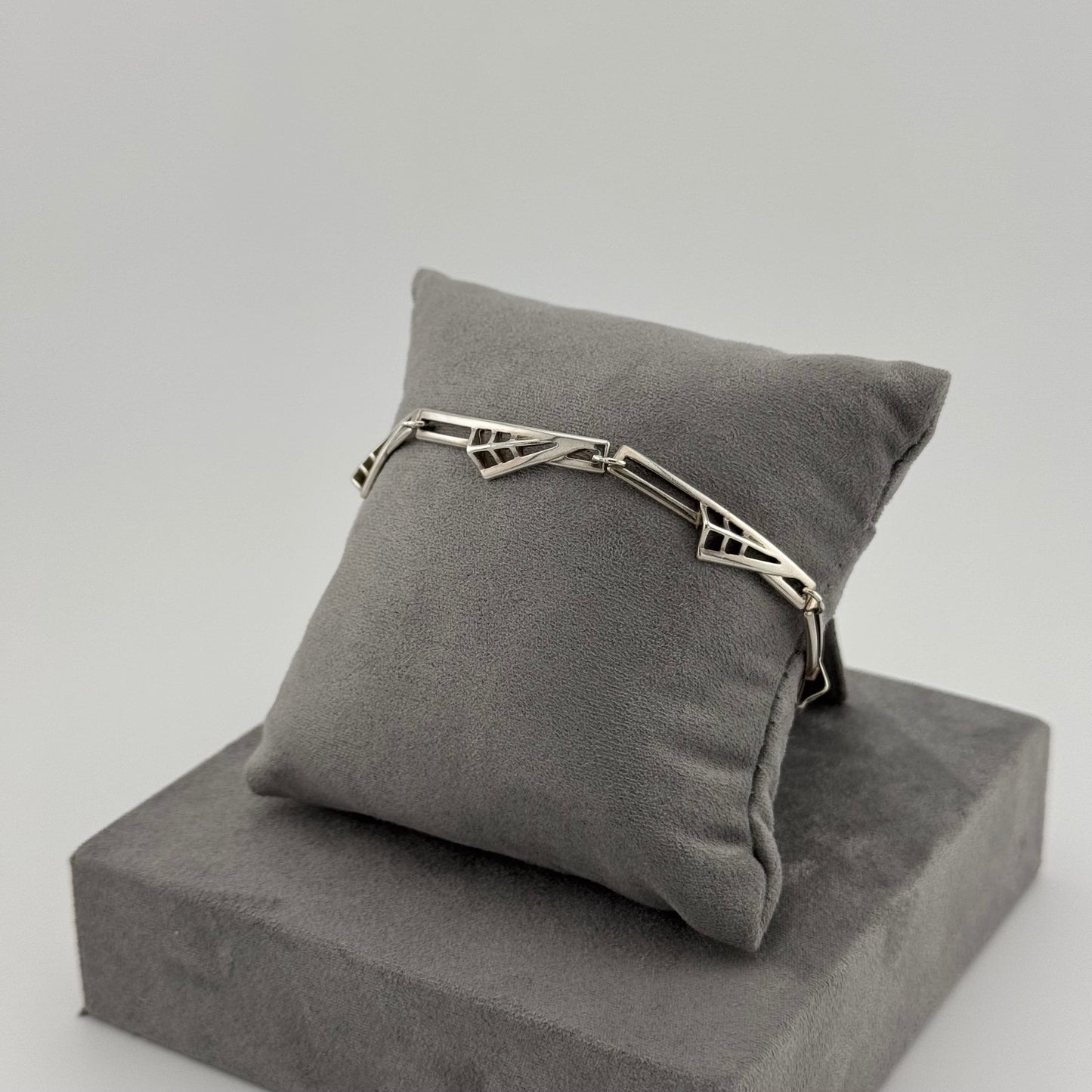 sterling silver geometric bracelet on a grey suede cushion 