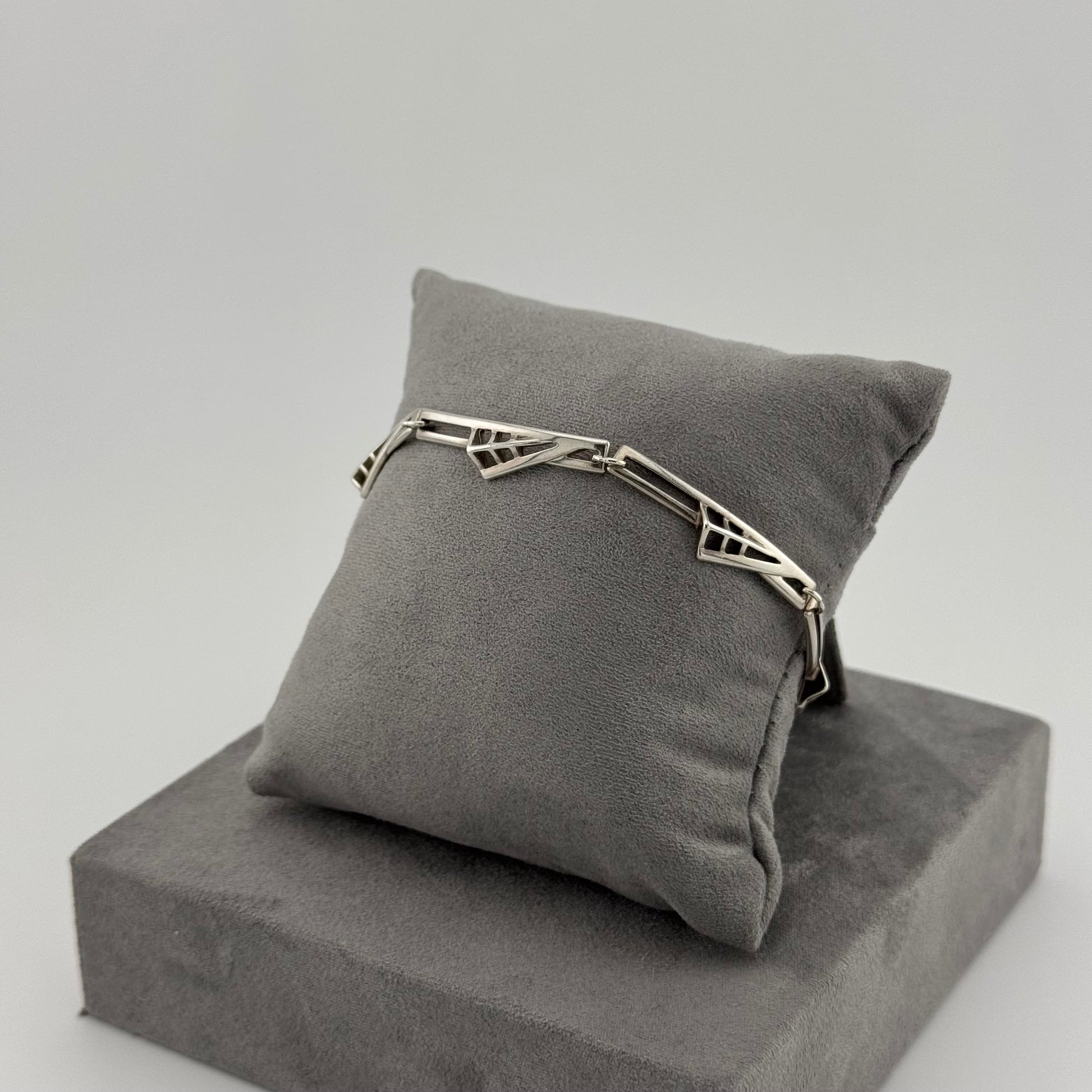 sterling silver geometric bracelet on a grey suede cushion 