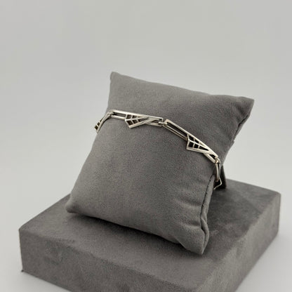 sterling silver geometric bracelet on a grey suede cushion 