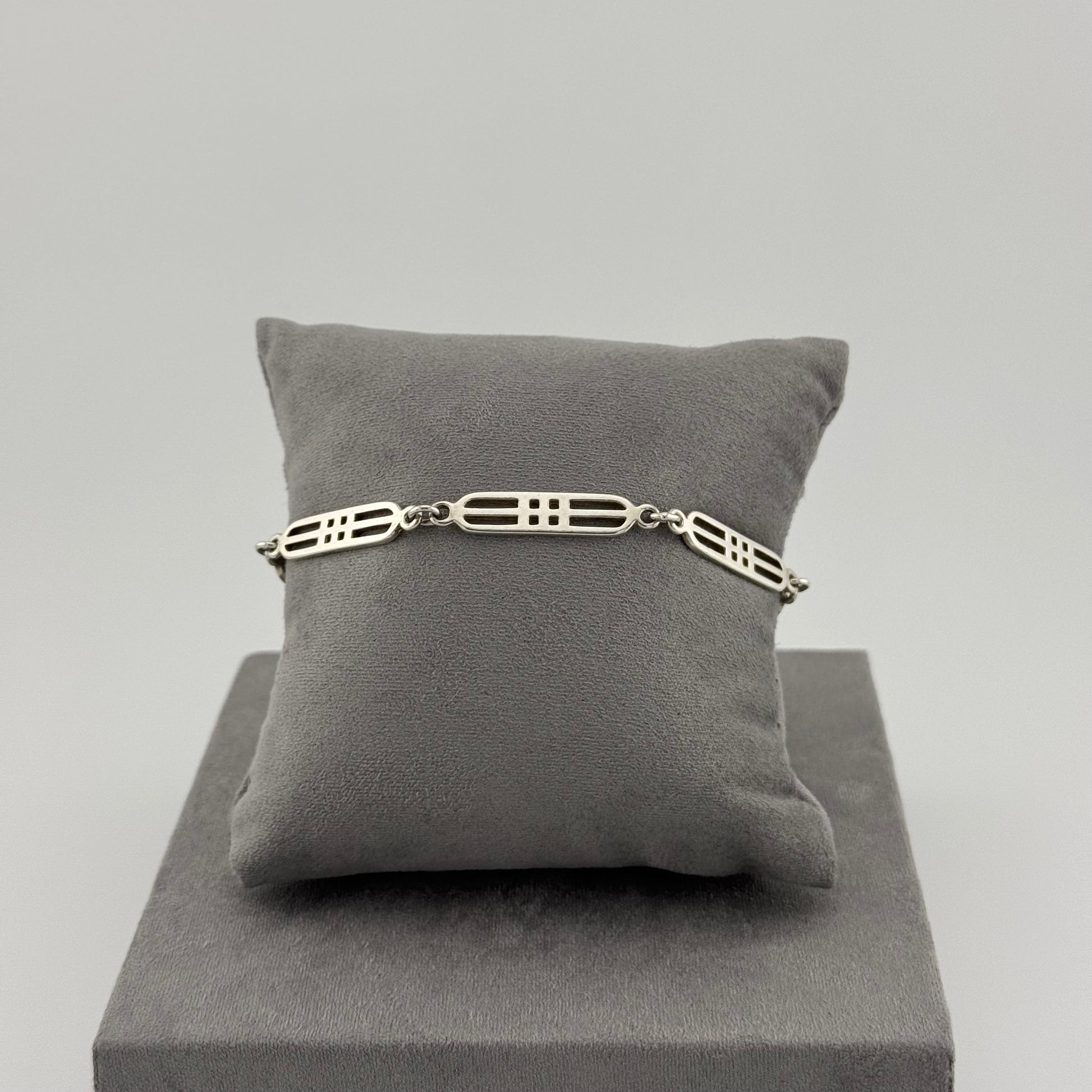 sterling silver geometric bracelet on a grey cushion