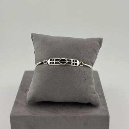 sterling silver kit heath bracelet displayed on a suede grey cushion 