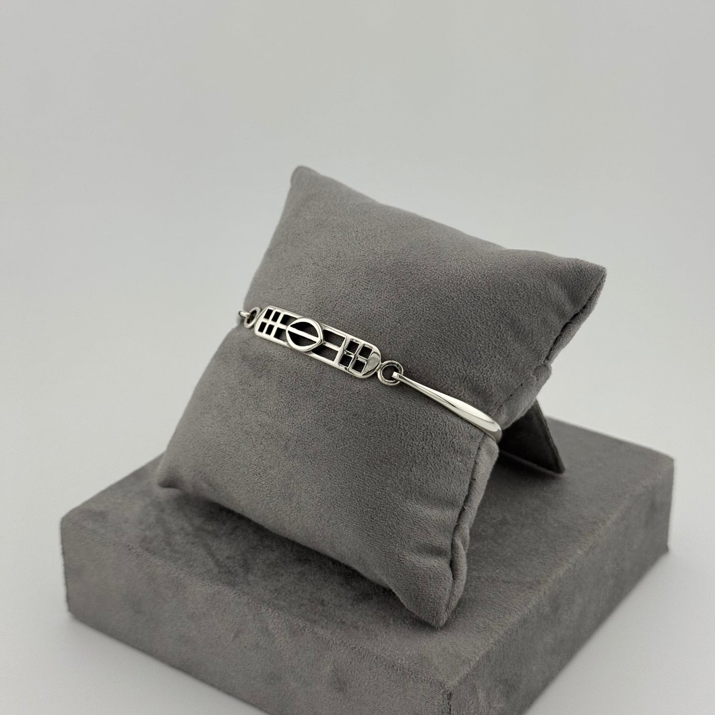 sterling silver kit heath bracelet displayed on a suede grey cushion 