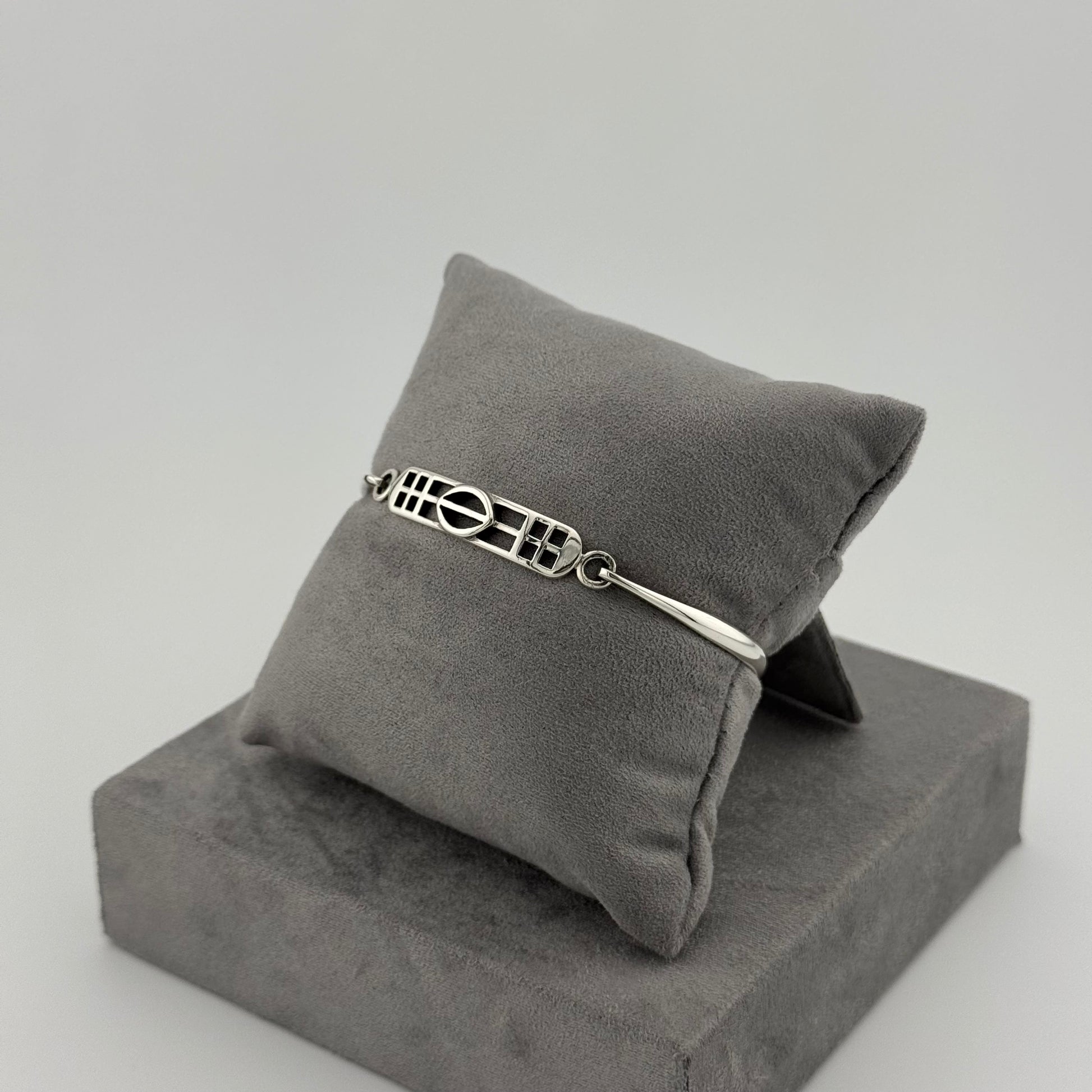 sterling silver kit heath bracelet displayed on a suede grey cushion 