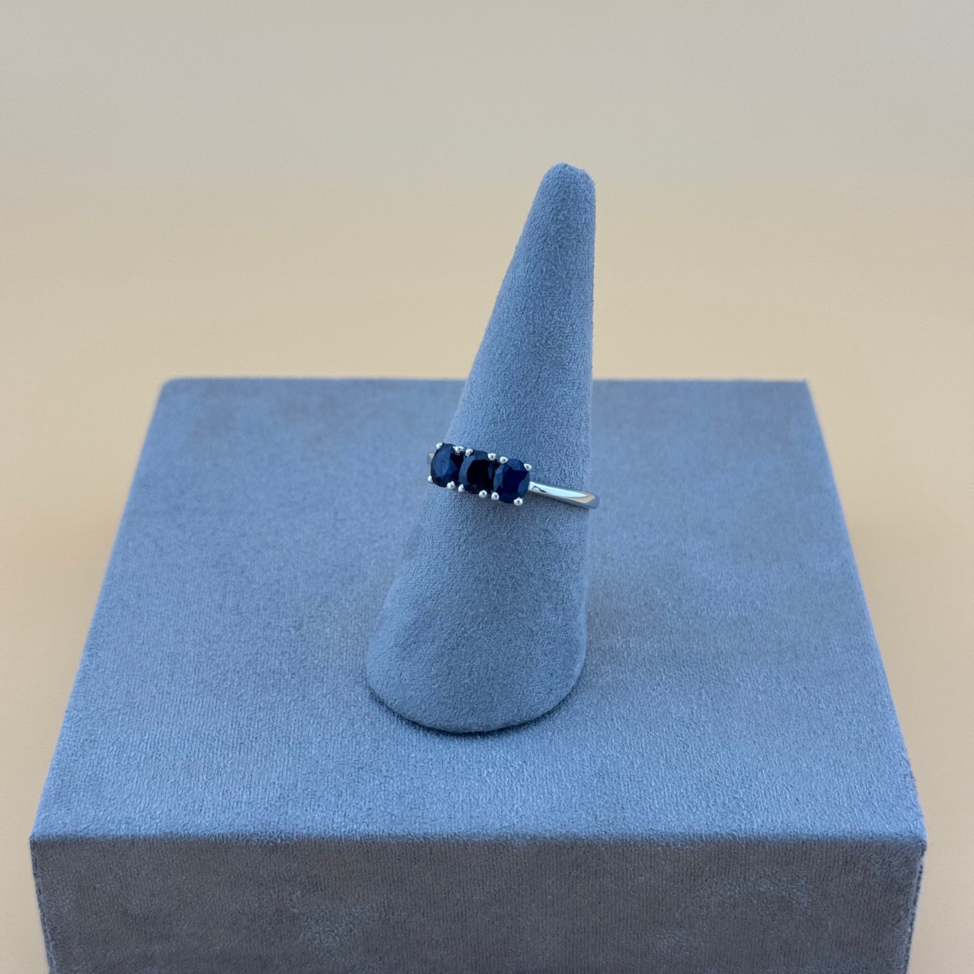 Ring with blue stones on a blue ring stand against a beige background