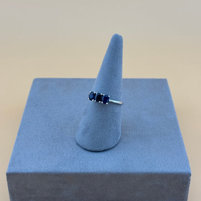 Ring with blue stones on a blue ring stand against a beige background