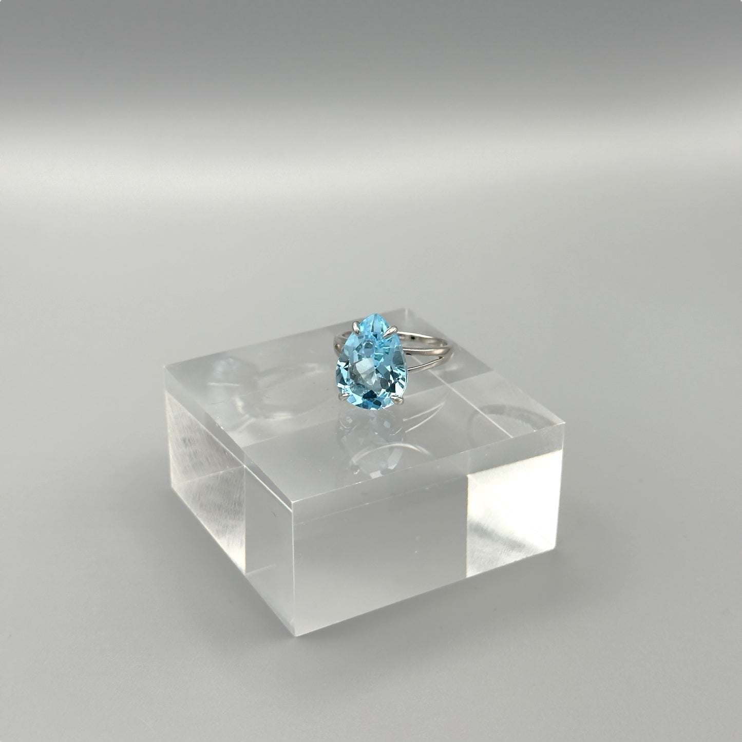 Side view of aquamarine ring on clear display cube