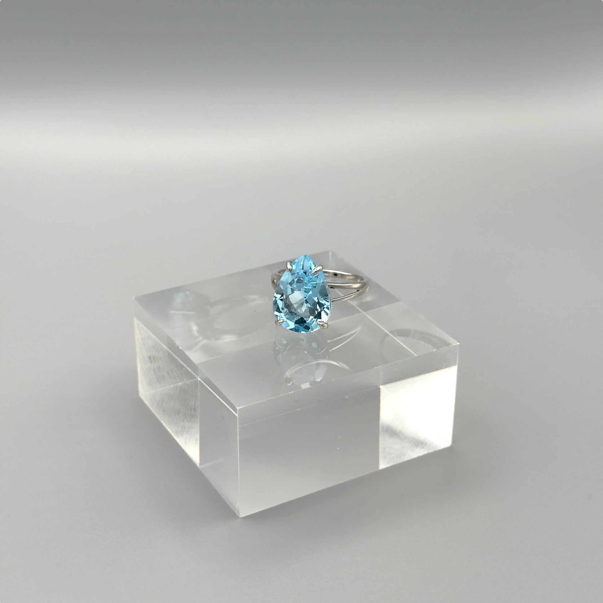 Side view of aquamarine ring on clear display cube