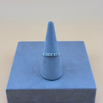 Silver aquamarine ring on a blue cone-shaped jewelry display against a beige background