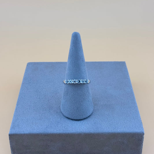 Silver aquamarine ring on a blue cone-shaped jewelry display against a beige background