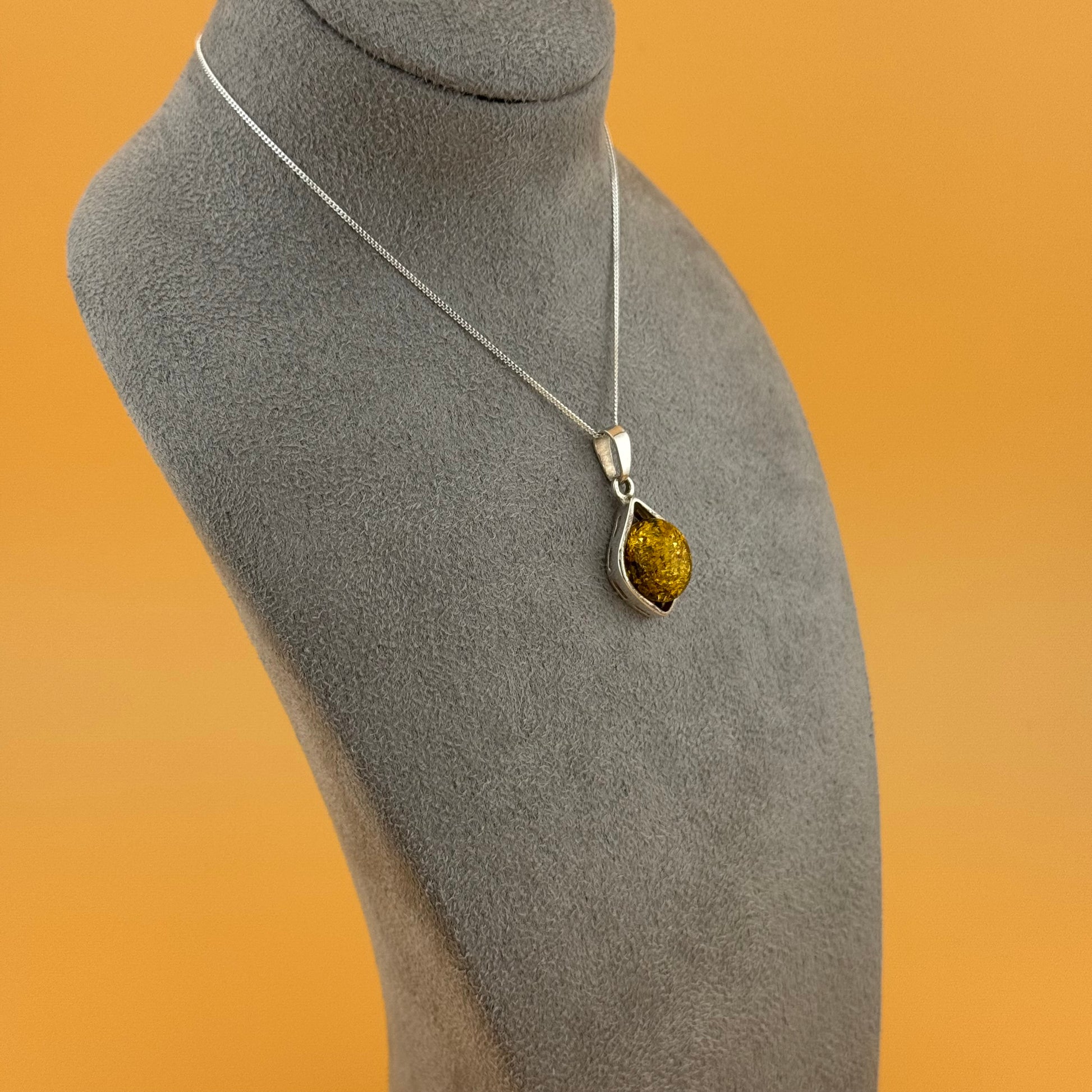 Necklace with a pendant on a mannequin bust against an orange background