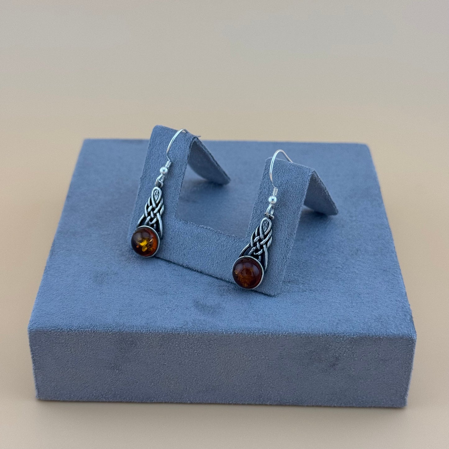 Silver amber earrings with amber stones on a blue jewelry display box.