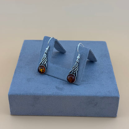 Silver amber earrings with amber stones on a blue jewelry display box.