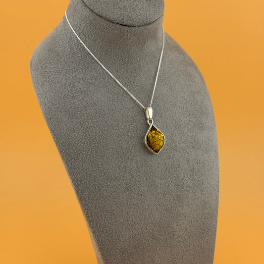 Silver necklace with a pendant on a mannequin bust against an orange background