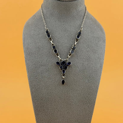 Necklace with purple stones on a gray mannequin bust against an orange background