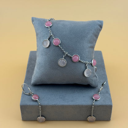 Bracelet with rose quartz pink and silver charms on a gray cushion against a beige background
