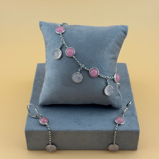 Bracelet with rose quartz pink and silver charms on a gray cushion against a beige background