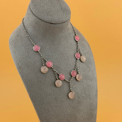 Necklace with pink and silver rose quartzcircular pendants on a gray mannequin bust against an orange background