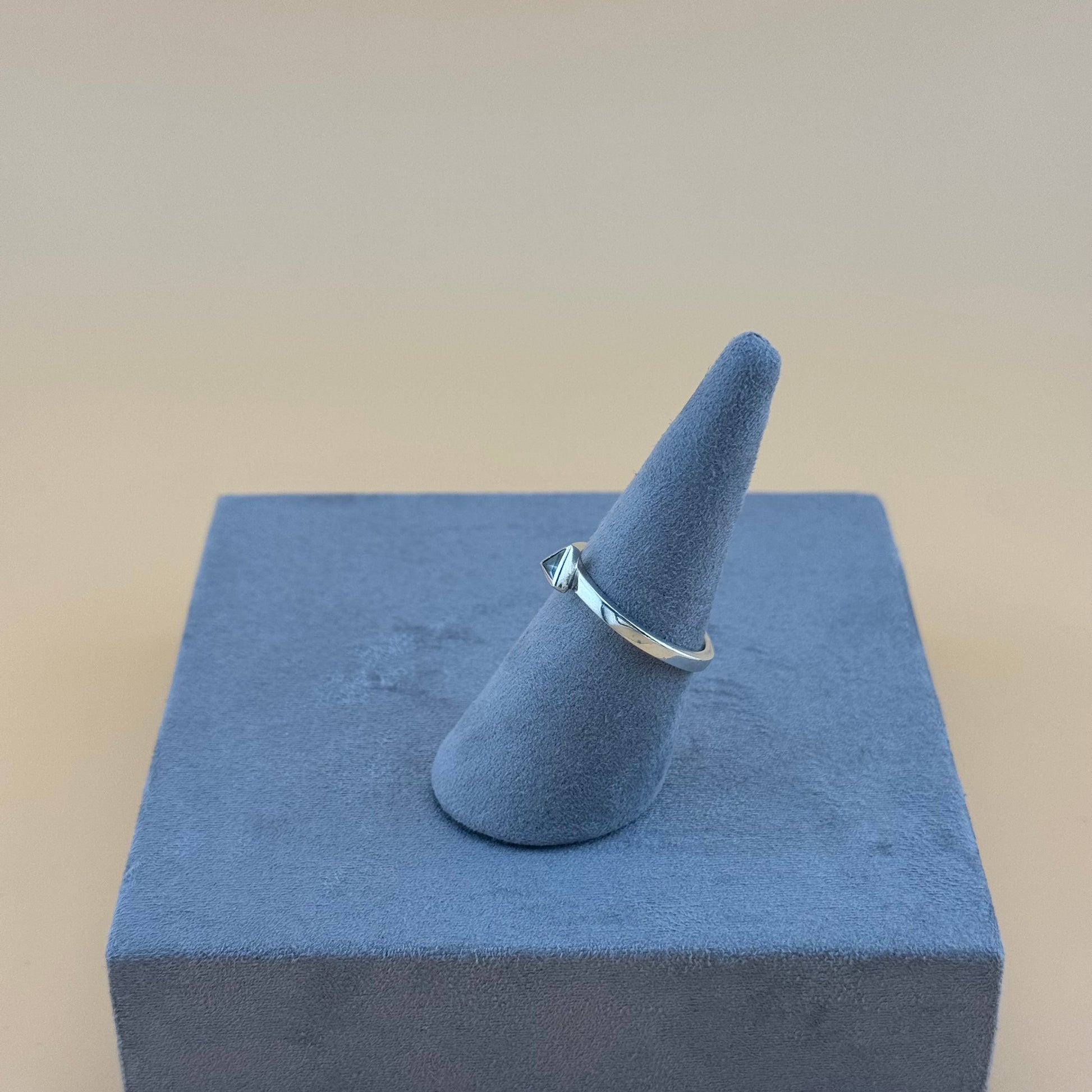 Silver ring on a blue ring stand against a beige background