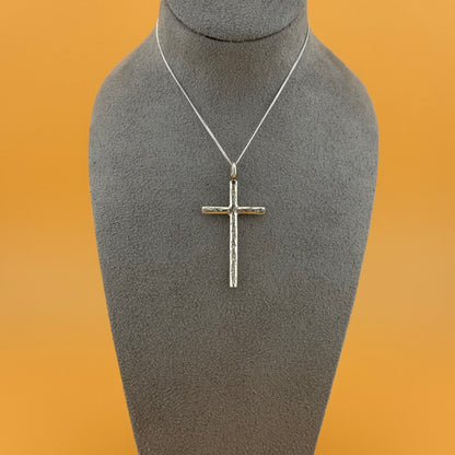 Silver cross pendant on a gray mannequin bust with an orange background