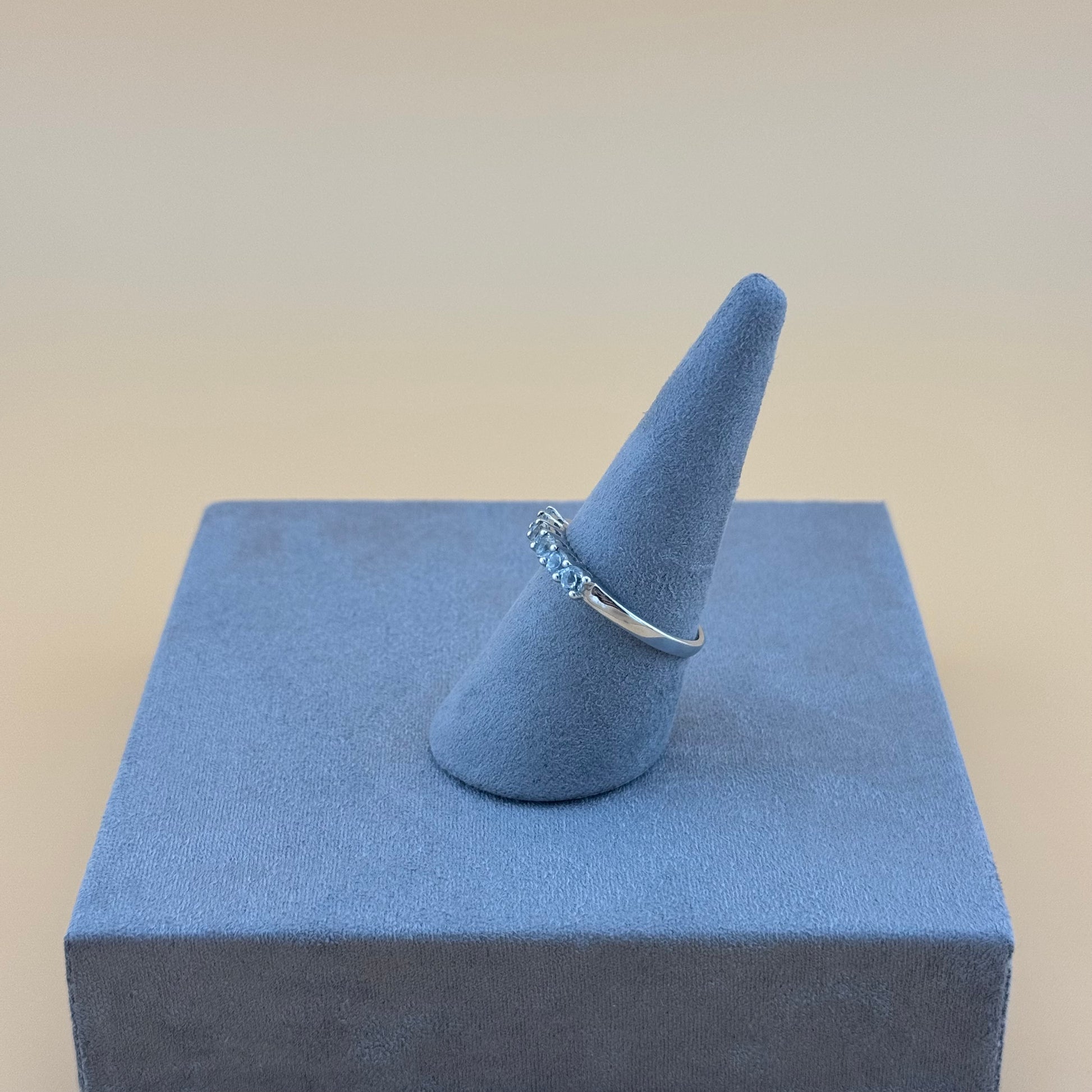 Silver ring on a blue ring stand against a beige background