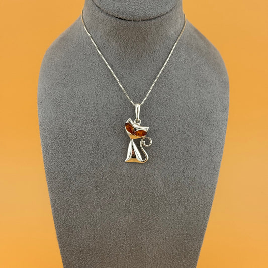 Silver necklace with a cat-shaped pendant on a gray mannequin bust against an orange background